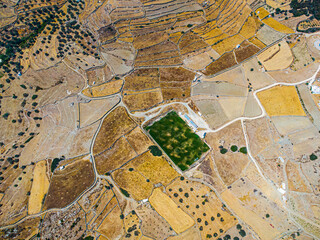 Aerial view on a green football field during drought on sifnos island, Greece - obrazy, fototapety, plakaty