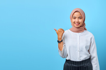 Portrait of smiling young Asian woman pointing to empty space with finger