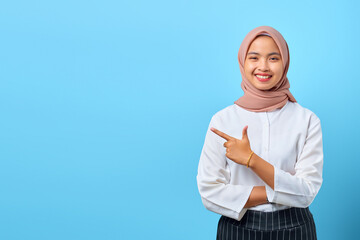Portrait of smiling young Asian woman crossed arms and pointing to empty space