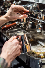 Fototapeta na wymiar Closeup image of male hands pouring milk and preparing fresh cappuccino, coffee artist and preparation concept, morning coffee