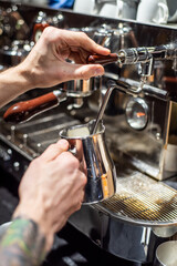 Fototapeta na wymiar Closeup image of male hands pouring milk and preparing fresh cappuccino, coffee artist and preparation concept, morning coffee