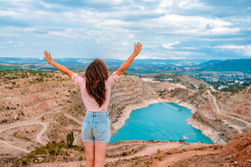 A happy young beautiful woman at the Kadykovsky quarry in the shape of a heart with turquoise water in the Crimea. Beautiful landscape