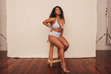 Young woman sitting comfortably in blue underwear - obrazy, fototapety, plakaty