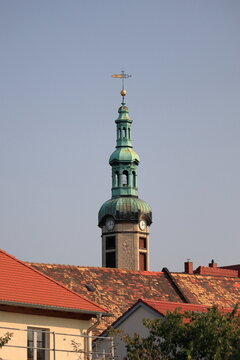 Historischer Kirchturm der Auenkirche mit gr&uuml;ner Barockhaube &uuml;ber roten Ziegeld&auml;chern bei klarem Himmel, Markkleeberg, Sachsen, Deutschland