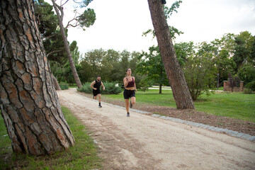 young caucasian man and woman couple running in a park