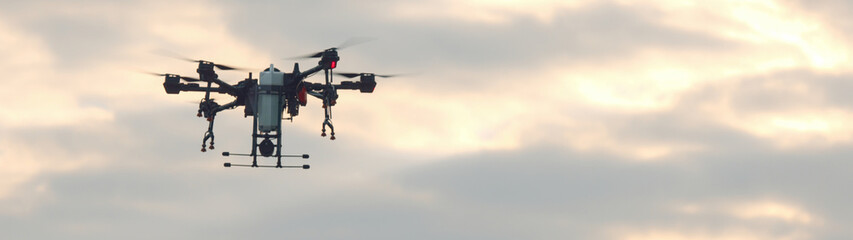 View of a huge intelligent agriculture drone with spray nozzles flying over corn field early in the morning