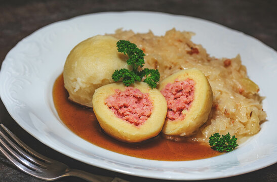 Wurstknödel mit Sauerkraut auf Bratensaft. Filled dumplings with colesalad and Bacon
