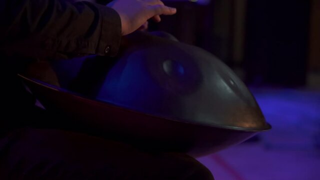 Close up view of musician hands playing handpan drum on big concert hall stage