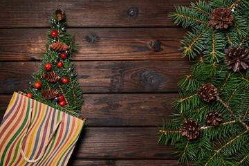 Fir branches in the form of a christmas tree in a paper bag on a wooden background with copy space