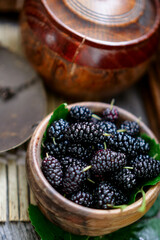 Ripe black mulberries in summer, freshly picked in wooden bowl