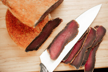 beef basturma with a knife on a board in spices