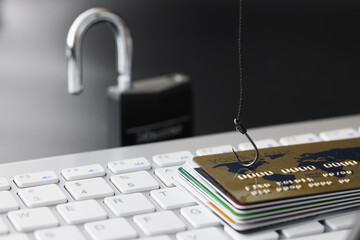 Plastic bank credit cards and fishhook on computer keyboard