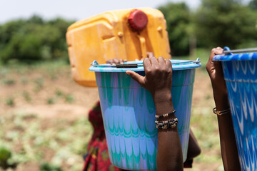 Close up of colorful water containers carried on the head by some black African girls not shown in the picture; drought and child labour concept