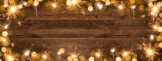 Frame of lights bokeh golden flares and sparkler isolated on rustic brown wooden texture - Holiday...
