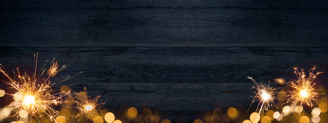 Frame of lights bokeh golden flares and sparkler isolated on rustic dark blue wooden texture -...