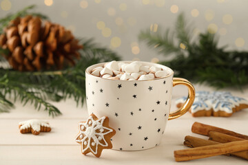 Delicious hot chocolate with marshmallows, gingerbread cookies and cinnamon on white wooden table...