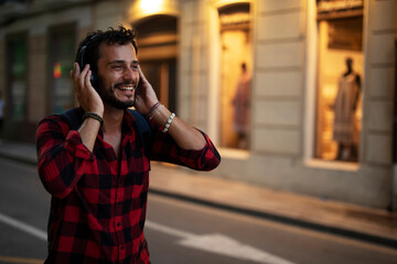 Young man listening to music. Urban fashion man with headphones enjoying the city