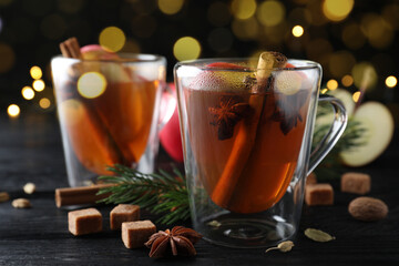 Aromatic hot mulled cider on black wooden table, closeup