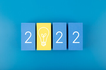 2022 numbers with light bulb on dark blue background. Trendy minimal concept of new ideas and inspirations