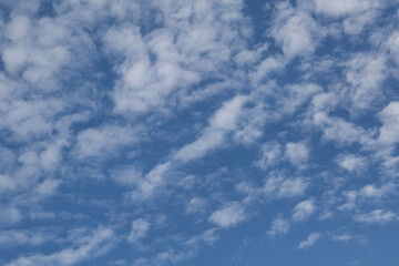 Fragment of the blue sky with white clouds. Textured abstract background