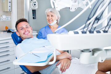 Male patient with professional stomatologist in dentist office waiting for a dental procedure. Focus on man