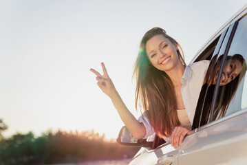 Photo portrait smiling woman riding in car looking in window in shirt showing v-sign gesture