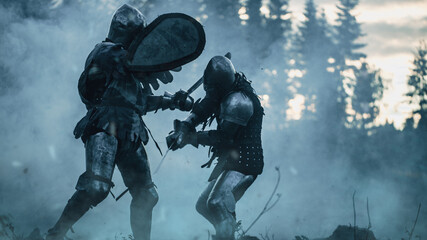 Dark Age Battlefield: Two Armored Medieval Knights Fighting with Swords. Battle of Armed Warrior Soldiers, Killing Enemy in Mysterious Forest. Cinematic Smoke, Mist, Light in Historic Reenactment - obrazy, fototapety, plakaty