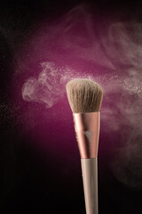 cosmetic brush with stream splash dusty plume of cosmetics on red background