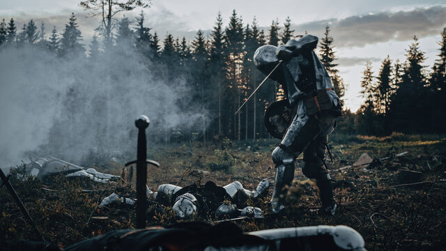 Dark Age Battlefield: Brutal Fight to Death of Two Armored Medieval Knights, Killing Enemy with Sword. Battle of Armed Warrior Soldiers. Dramatic Scene, Cinematic Smoke, Light in Historic Reenactment