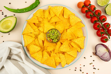 A delicious plate of tortilla nachos with guacamole sauce, jalapenos, red onions, tomatoes, limes, avacados, olives and salsa.