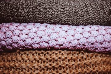Three knitted cozy warm winter sweaters lying in a row