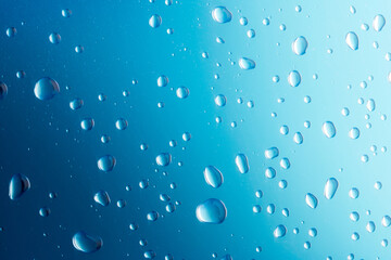 Water drops on blue background. Drops of water on surface. Macro photo. Splash pattern.