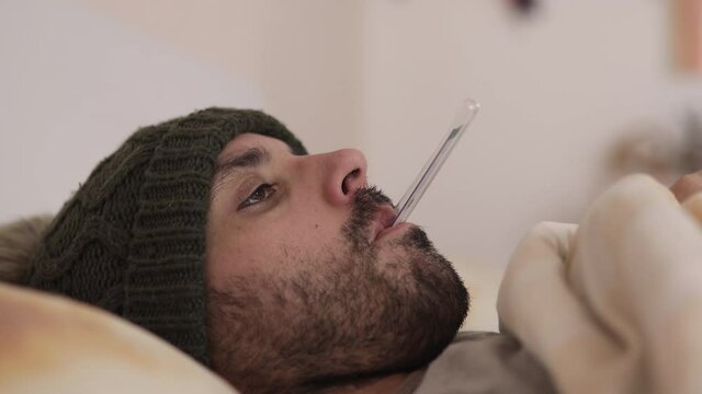 Man measuring fever with thermometer in the mouth. Concept of sickness