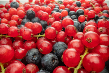 Various fresh wild berries on a black glass background, side view. Berry mix. Lingonberry, strawberry.