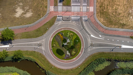 Top down aerial view of a traffic roundabout on a main road in an urban area