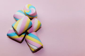 Closeup of heap of colorful marshmallows candy on a pink background