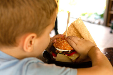 a boy eats a hamburger in a cafe