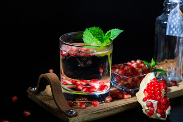 two colorful summer cocktails with pomegranate and mint on a black table