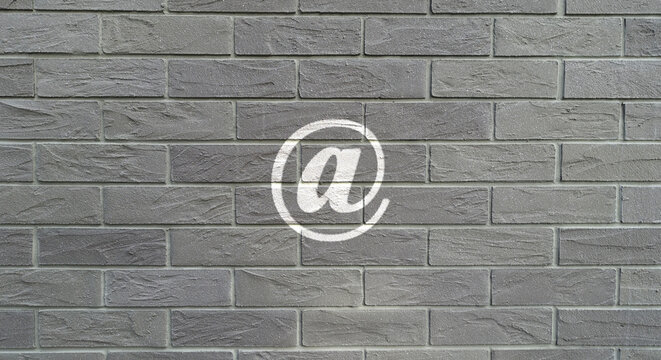 @-Zeichen auf einer Backsteinwand