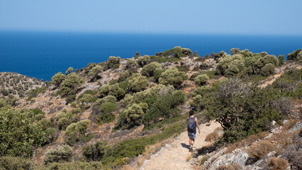 Woman hiking on a path into the mountains of Crete under sun