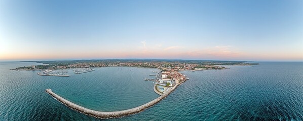 Drone panorama of the Croatian coastal town Umag taken during sunset above the harbor entrance with...