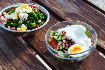 Fresh vegetables salad with eggs in bowls on wooden table.