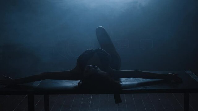 Silhouette of a sexy girl dancing an erotic sensual dance in blue smoke.