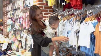 indonesian mother shopping clothes for her son in the baby boutique store
