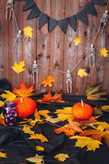 Halloween background with pumpkin, skeletons and autumn map leaves