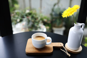 Coffee in a white cup with yellow gerbera flower