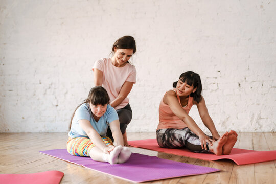 Young Woman With Down Syndrome Doing Exercise During Yoga Group Class