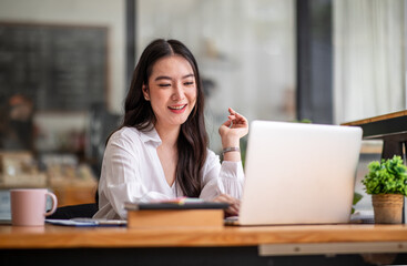 Shot of an Asian young business Female working on laptop computer in her workstation.Portrait of Business people employee freelance online report marketing e-commerce telemarketing concept.