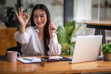 Shot of an Asian young business Female working on laptop computer in her workstation.Portrait of Business people employee freelance online report marketing e-commerce telemarketing concept.