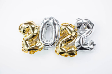 Banner. Happy New Year holiday. Balloons made of gold and silver foil with the number 2022 on a white background. Flat lay.